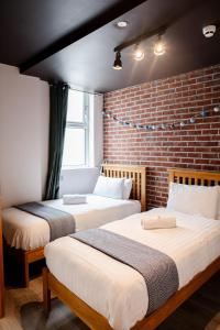 戈尔韦内斯特精品旅舍的砖墙客房的两张床