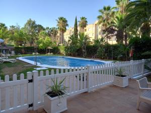 两姐妹Hotel TRH La Motilla的棕榈树游泳池周围的白色围栏