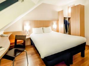 瓦讷宜必思瓦纳酒店的卧室配有一张白色大床和一张书桌
