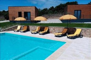 特兰科苏Trancoso Ecohouse的一座带椅子和遮阳伞的游泳池位于一座建筑旁边