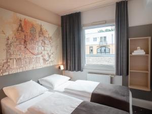 什未林B&B Hotel Schwerin-Süd的配有窗户的酒店客房内的两张床