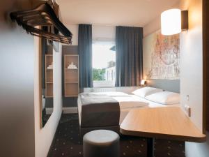 什未林B&B Hotel Schwerin-Süd的酒店客房设有两张床和一张桌子。