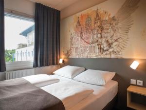 什未林B&B Hotel Schwerin-Süd的一间卧室设有两张床,墙上挂着一幅画