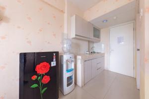 加拉旺RedLiving Apartemen Grand Sentraland - Dragon Apartel Tower Pink的厨房配有黑色冰箱,上面涂有玫瑰花