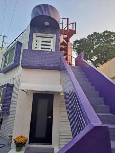 统营市Dongpirang Purple House 2的一座带紫色楼梯栏杆和楼梯箱的房子