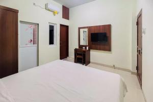 棉兰Teratai Residence Mitra RedDoorz的卧室配有白色的床和书桌