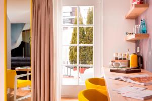 萨尔茨堡Small Luxury Hotel Goldgasse的客房设有一张带黄色椅子的桌子和一扇窗户。