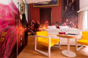 萨尔茨堡Small Luxury Hotel Goldgasse的一间设有黄色椅子、桌子和绘画的房间
