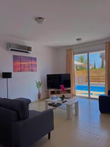 珊瑚湾3 Bedroom Coral Bay Beach Seaview Villa II Private Pool的带沙发、电视和桌子的客厅