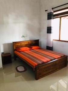 高尔Sanithu Homestay Galle的一间卧室配有带橙色床单的床和窗户。