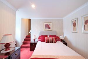 阿伯丁The Jays Guest House的一间卧室配有一张带红色枕头的床和楼梯