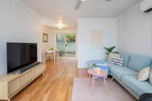 纽卡斯尔Tighes Hill Hideaway - Alfresco Living by the Park的客厅配有蓝色的沙发和平面电视。