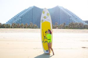 金兰Cam Ranh Nha Trang Seaview Resort的一名妇女站在海滩上的冲浪板旁边
