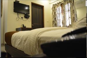 莫尔穆冈HOTEL AVISHA Residency的卧室配有一张床铺,墙上配有电视