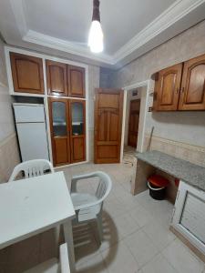 甘达坞伊港Appartement S2 Kantaoui vue mer的厨房配有木制橱柜和白色的桌椅