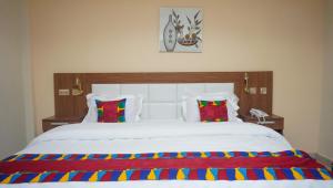 塔科拉迪RHOGEM Hotel的卧室配有一张带彩色枕头的大型白色床。