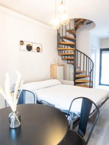 阿维拉VUT Adarve的客房设有两张床、一张桌子和一个螺旋楼梯。