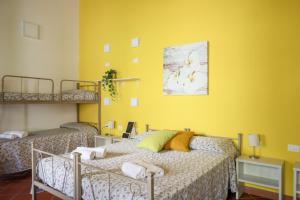 庞贝B&B Pompei Hostel Deluxe的一间卧室设有两张床和黄色的墙壁