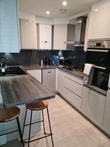 伦敦2 bed Home From Home Apartments的厨房配有白色橱柜、桌子和凳子