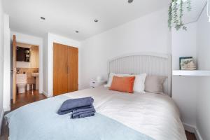 伦敦Arte Stays - 3-Bed 3-Bath Nordic Style Minimalistic Flat, Hackney Downs station 2 min walk, Great Location, Parking, Weekly or Monthly stays, Serviced Accommodation - 6 people的卧室配有白色的床,上面有橙色和蓝色的毛巾