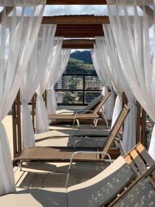 圣洛伦索Flat lindo com piscina e linda vista da cidade的阳台上的一组椅子,配有白色窗帘