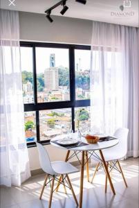 圣洛伦索Flat lindo com piscina e linda vista da cidade的配有大窗户的客房内的桌椅