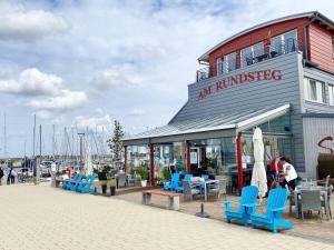 费曼城堡Motoryacht-Futura-Urlaub-im-Yachthafen的码头上一座带蓝色桌椅的建筑