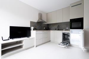 罗兹Brzeska 22的厨房配有白色橱柜和平面电视。