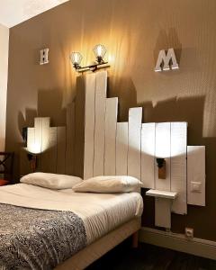 奥弗涅库尔农Hotel Le Midi Clermont-Cournon的卧室配有一张带两盏灯的墙壁床。