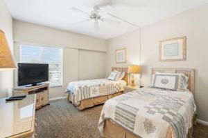 Point O'RocksIsland House Beach Resort 13S的一间卧室配有两张床和一台平面电视