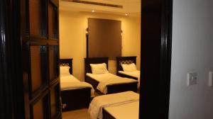 阿布扎比International Abu Dhabi Hostel的带3张白色床单的床的房间