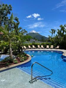福尔图纳Hotel Boutique Casa Del Rio的一个带椅子的游泳池,后方是一座山。