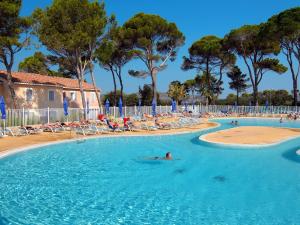 AubaisWell kept holiday home between Nimes and Montpellier的在游泳池里游泳的人,游泳池里摆放着椅子和树木