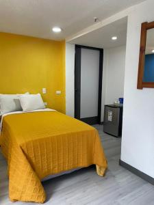 加拉加斯Hotel Renovación的一间卧室设有黄色的床和黄色的墙壁