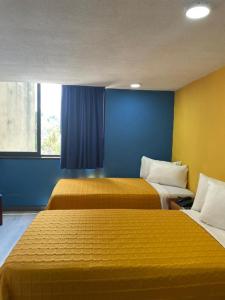 加拉加斯Hotel Renovación的两张床位于带蓝色和黄色墙壁的客房