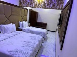 卡拉奇Defence Orchard DHA Karachi的酒店客房,配有两张带白色床单的床