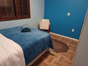 卡内拉Casa na Serra Gaucha Canela的一间卧室配有一张带蓝色毯子和椅子的床