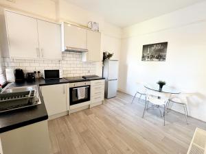 NorburyNorbury House - Apartment 1A的厨房配有白色橱柜和一张带桌子的小桌子。