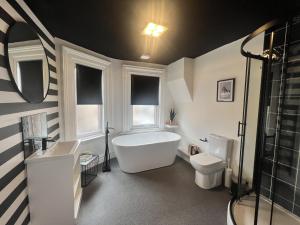 特伦特河畔斯托克One Battison - Affordable Rooms, Suites & Studios in Stoke on Trent的带浴缸、盥洗盆和卫生间的浴室