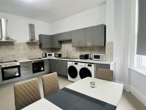 特伦特河畔斯托克One Battison - Affordable Rooms, Suites & Studios in Stoke on Trent的厨房配有灰色橱柜和桌椅