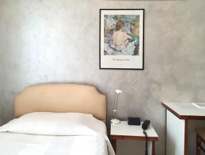 米兰莫里斯酒店的卧室配有一张床,墙上挂着一幅画