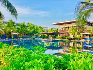 富国Sonaga Beach Resort & Villas Phu Quoc的一个带蓝椅和棕榈树的度假村游泳池
