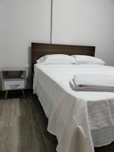 阿卡西亚斯Hotel Guadalupe Acacías的一张铺有白色床单的床和木制床头板