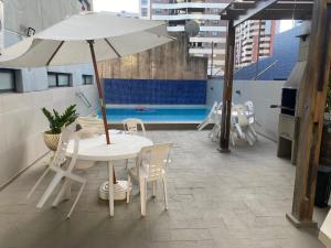 马塞约Confortável quarto e sala com Manobrista, Wi-fi, Tv Smart - Apto 208的屋顶上配有白色桌椅和遮阳伞