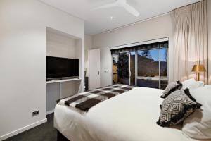 弗兰克顿Queenstown Hot Tub Apartment的白色的卧室设有一张大床和一个大窗户