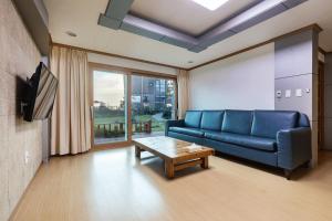 西归浦市The Bay Jeju Resort的客厅配有蓝色的沙发和桌子