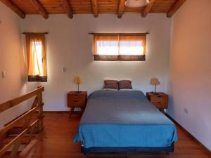 卡皮亚德尔德尔蒙特Cabaña La Yumba的一间卧室设有蓝色的床和2个窗户。