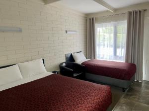 凯恩顿Central Highlands Motor Inn的客房设有两张床、一把椅子和窗户。