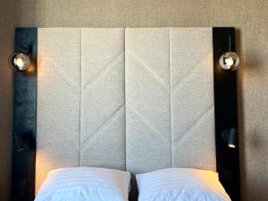 罗瓦涅米圣塔斯圣诞老人酒店的床头板,配有两个白色枕头和两个灯