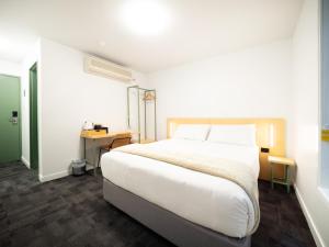 布里斯班YHA Brisbane City的卧室配有一张白色大床和一张书桌